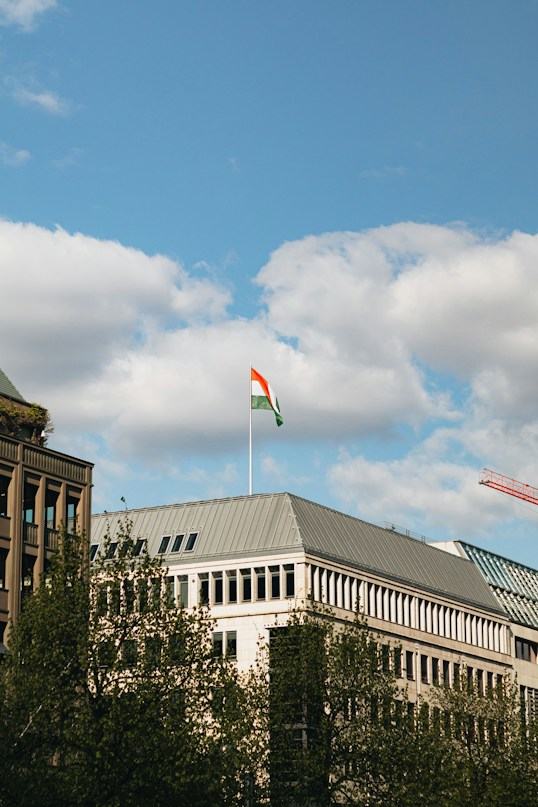 An office building under a blue sky with the Indian flag flying above it